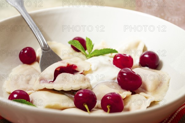 Traditional dumplings with cherries and yogurt, close-up, no people