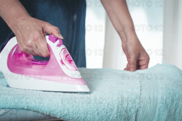 Ironing clothes at home, in a bright room, with natural light, female hands