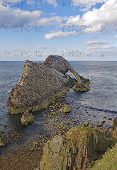 Remarkable rock formation jutting into the sea under a blue sky with few clouds, Bow Fiddle Rock,