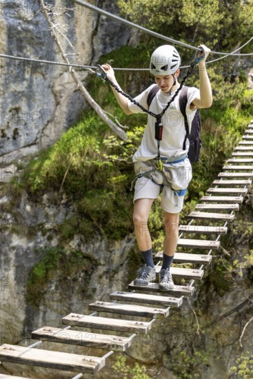 Mountaineer climbing over a suspension bridge on the Isidor via ferrata, GrÃ¼nstein, Schönau am