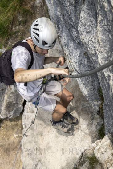 Mountaineer climbing over a steep wall in the Isidor via ferrata, GrÃ¼nstein, Schönau am Königssee,