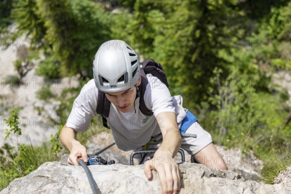 Mountaineer climbing over a steep ladder in the Isidor via ferrata, GrÃ¼nstein, Schönau am