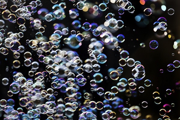 Many, small iridescent and floating soap bubbles against a black background, Recklinghausen, North