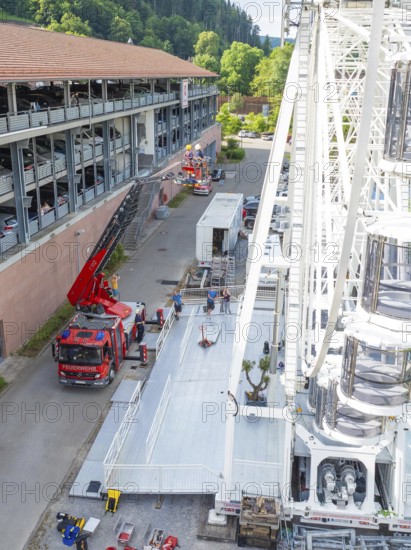 Construction of a Ferris wheel near a road with fire engines and people, fire brigade exercise for