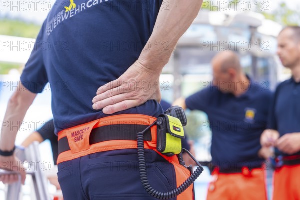 Firefighters in uniform talk to each other, one wears a radio on his belt, fire brigade exercise