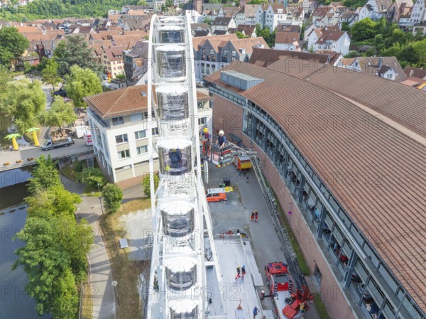 View of a Ferris wheel in a city with surrounding buildings and people in summer, fire brigade