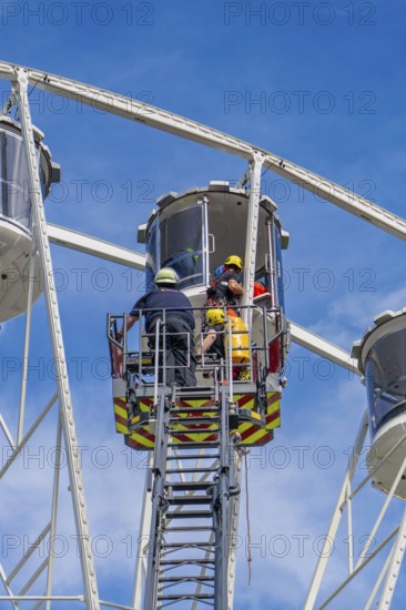 Rescue workers help a person in a giant wheel cabin, fire brigade exercise for gondola rescue,
