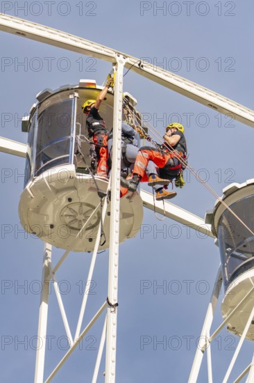 Two workers in protective clothing carry out inspections on a Ferris wheel, fire brigade exercise
