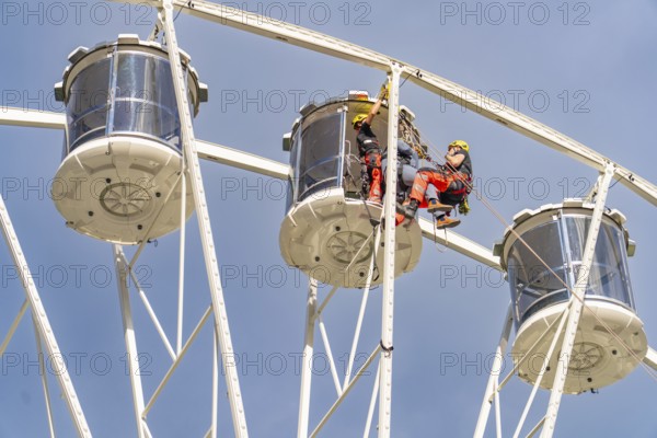 Two workers in equipment working on the structure of a Ferris wheel, fire brigade exercise for