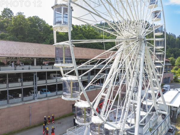 View of a Ferris wheel in a city, firefighters on site, fire brigade exercise for gondola rescue,