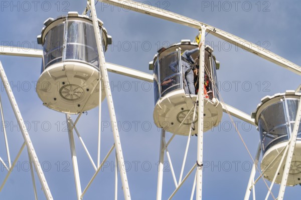 Detailed view of two giant wheel cabins in front of a clear blue sky, fire brigade exercise for