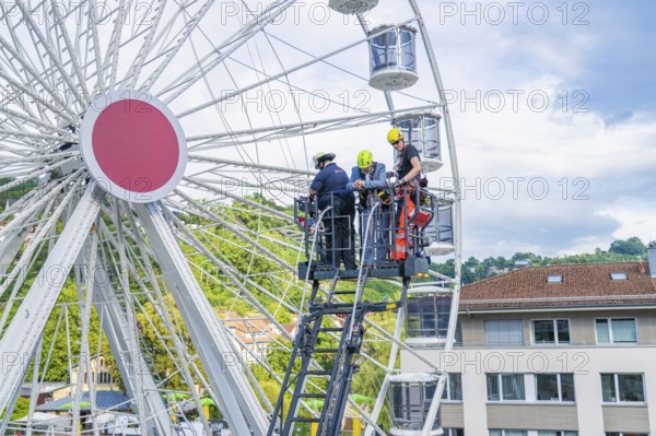 Firefighters carry out rescue operation on a Ferris wheel in a city, fire brigade exercise for
