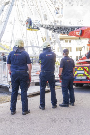 Three firefighters in uniforms standing in front of emergency vehicle with lifting platform, fire
