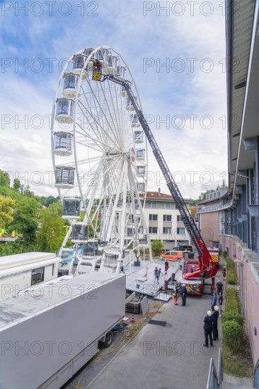 Fire brigade operation next to tall buildings with a Ferris wheel in the background, Fire brigade