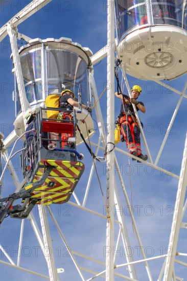 Worker with safety equipment during maintenance work on a Ferris wheel, fire brigade exercise for