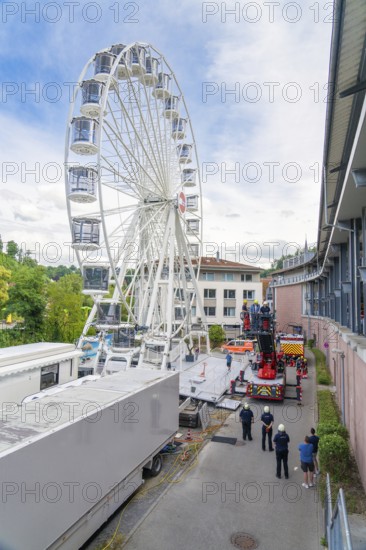 Fire brigade operation with a high Ferris wheel next to buildings with observers, fire brigade