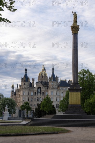 Schwerin Castle rises behind the Victory Column with golden statue, Schwerin,