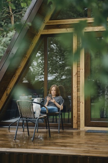Serene moment after the rain. Pretty woman is reading something on smartphone. She is seated