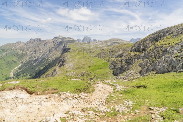 Expansive view of mountain landscape with green grass and blue sky full of clouds, Schlehrn hike,
