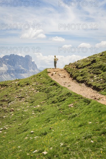 Hikers on a path in a mountainous landscape under a blue sky, Schlehrn hike, Alpe di Siusi,