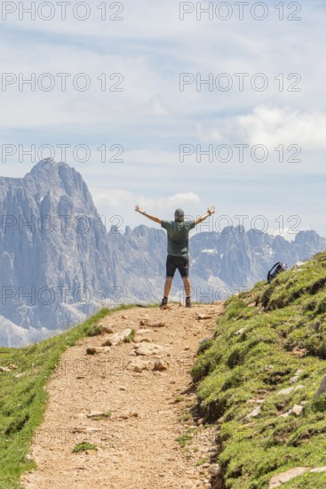 Person on a path with outstretched arms in front of a majestic mountain landscape, Schlehrn hike,