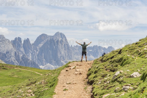Person with raised arms on a hiking trail in front of an impressive mountain panorama, Schlehrn