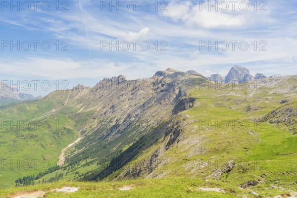 Extensive mountain landscape with green hills and blue sky in the background, Schlehrn hike, Alpe