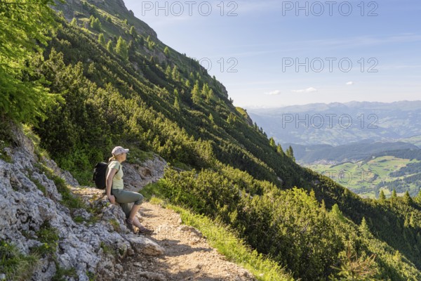 Hiker sitting on a mountain path with a view of the valley, hike to the Schlehrn, Alpe di Siusi,
