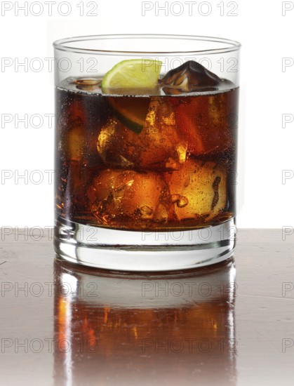Cocktail in a tumbler on ice with half a slice of lime as garnish against a white background,