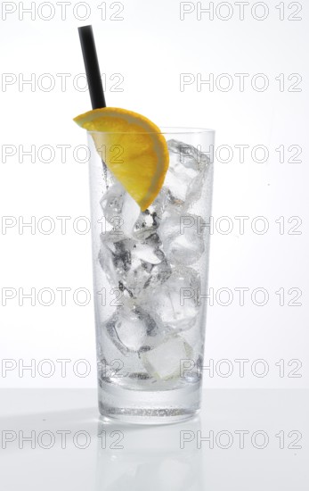 Betautes long drink glass, filled with ice cube cubes, half an orange slice as garnish, in front of
