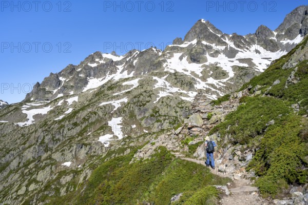 Mountaineer on hiking trail, summit of the Aiguilles rouges with snow remains, Chamonix,