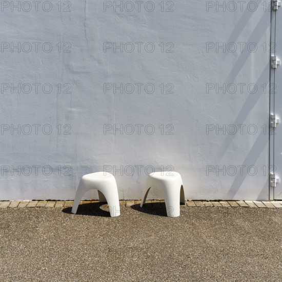 Two white plastic stools in front of a white wall, Elephant Stool, design Sori Yanagi, stackable,