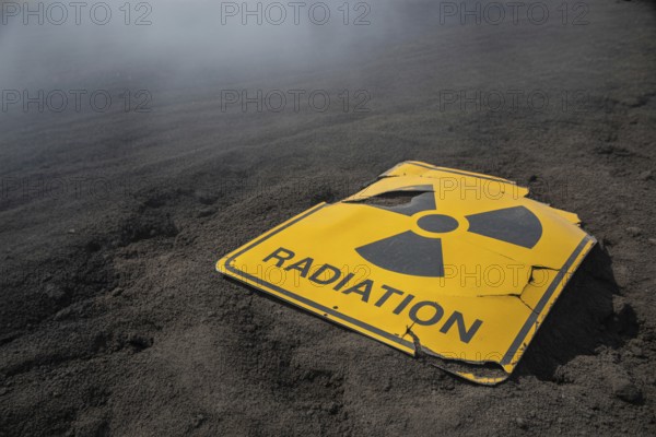 Damaged radiation warning sign in scorched earth. Symbol of catastrophe and nuclear ruin.