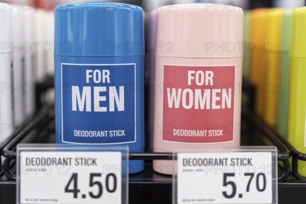 Close-up of gender-labeled deodorant sticks with unequal prices. Illustration of the pink tax in