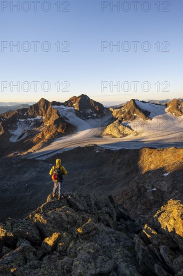 Mountaineers in front of a picturesque high mountain landscape at sunrise with alpenglow, glacier