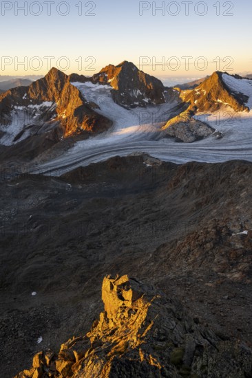 Picturesque high mountain landscape at sunrise with alpenglow, glacier and rocky mountain peaks in