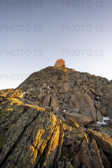 Stony summit of the Becher with mountain hut Becherhaus in the morning light at sunrise, Stubai