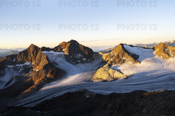 Picturesque high mountain landscape at sunrise with alpenglow, glacier and rocky mountain peaks in