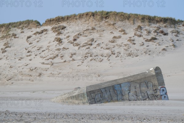 Abandoned bunker from the 2nd World War, sunken into the sand with graffiti, surrounded by sand