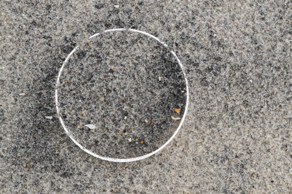 Remains of a plastic bottle in the sand on the beach, symbolising environmental pollution and human