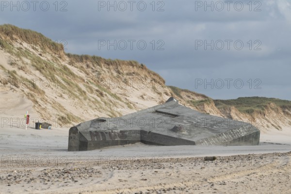 Abandoned bunker from the 2nd World War, sunken into the sand with graffiti, surrounded by sand
