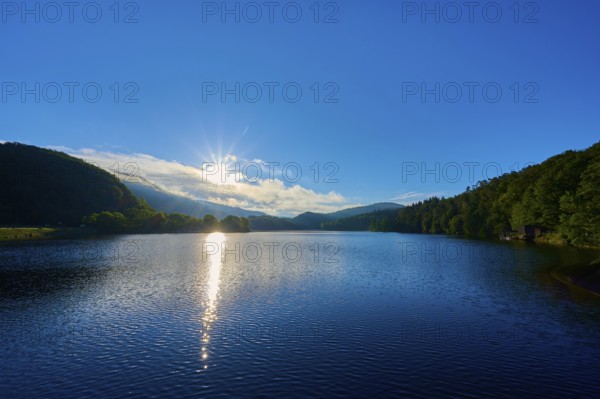 Lake in the morning light with sun, blue sky and surrounding mountains, summer, Rursee, Obersee,