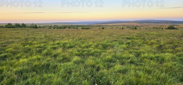 A wide moor landscape with a view of a sky illuminated by the colours of the sunset, summer, High