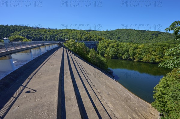 View of a large dam with dense forest under a clear blue sky, summer, Urft dam wall, Obersee,