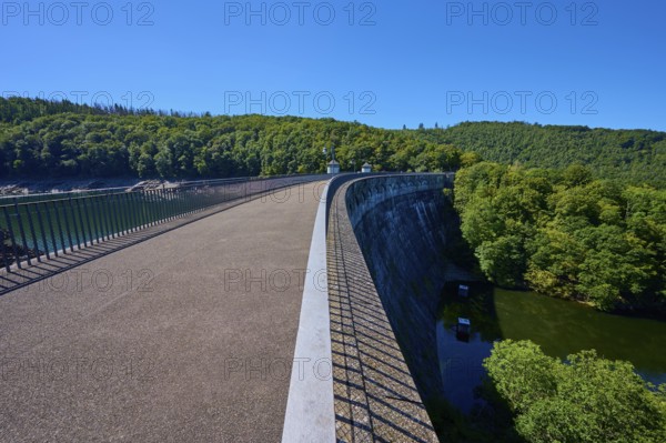 Long dam with neighbouring river and surrounding forest, clear sky, summer, Urft dam wall, Obersee,