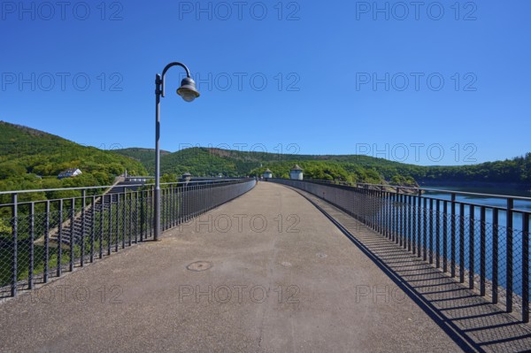 Asphalted bridge with railing over a water reservoir under a blue sky, summer, Urft dam, Obersee,
