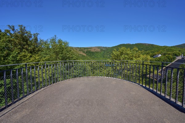 Viewing platform with railings in front of a wooded hilly landscape under a clear blue sky, summer,