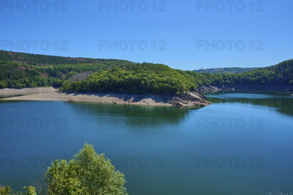 View of a lake with wooded shores and hills under a clear blue sky, summer, Urft dam wall, Obersee,