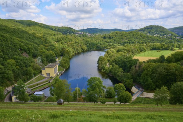 Quiet river dam surrounded by green hills and forests under a cloudy sky, summer, Rursee,