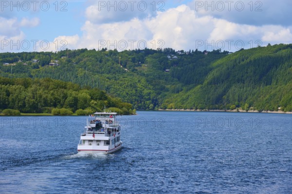 A passenger ship, stern view, sailing across a wide lake, surrounded by green hills, summer,